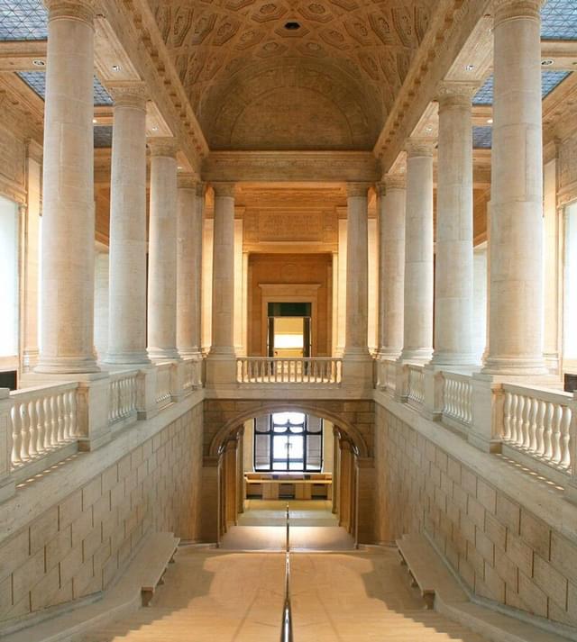 View down the stairs of a hallway with columns on either side inside the Asian Art Museum, San Francisco, CA.