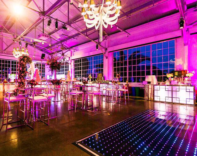 Interior event space with tables and chairs lit up with pink lighting at Fort Mason, San Francisco.