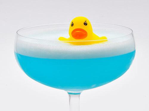 Rubber duck in a martini glass filled with a blue cocktail.