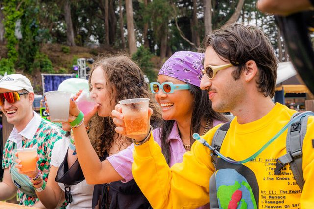 Line of people raising glasses at an outdoor event.