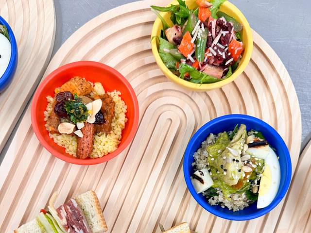 Wooden platter with a variety of salads and sandwiches.